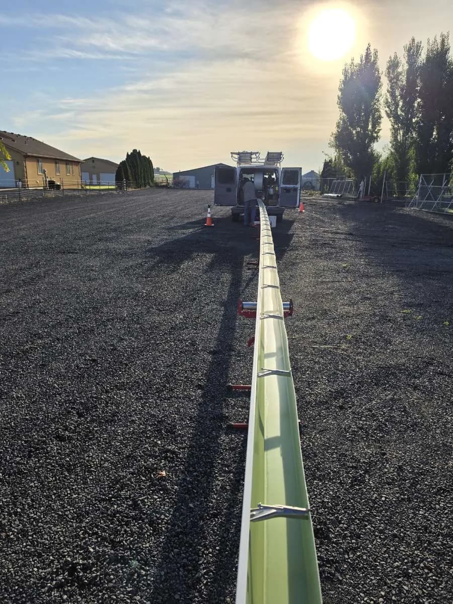 One continuous gutter run stretching across a gravel lot at sunrise